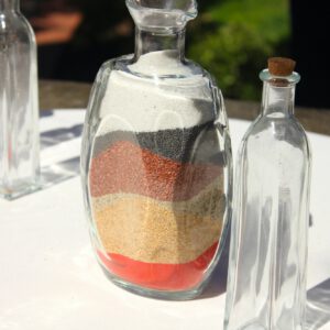Layers of sand in bottle for wedding ceremony on white table